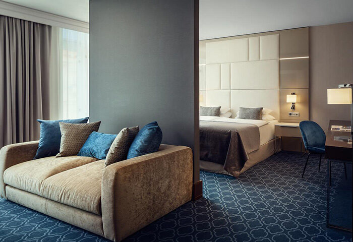 Hotel Kings Court, Prague. Luxurious suite with a plush sofa and a view into the bedroom, perfect for a gay honeymoon in Old Town.