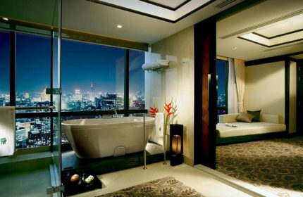 Banyan Tree Bangkok luxury hotel bathroom view. Top gay honeymoon choice in Bangkok. Bathtub overlooking the city skyline at night.