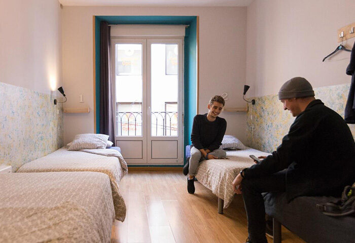 Sungate One, top gay hostel Madrid. Two men in a room with twin beds near a balcony. Gay-friendly lodging close to Chueca and Gran Via.