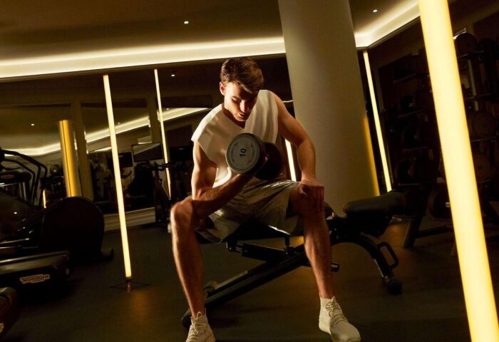 Gay-friendly Sofitel Barcelona Skipper hotel gym. Man lifting dumbbell. Top hotel in Barcelona center for gay men. Fitness center.