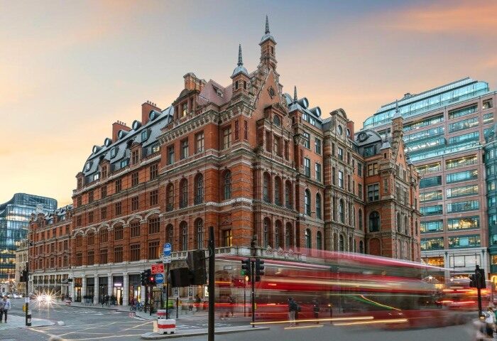 Andaz London Liverpool Street, a top gay hotel in London City Centre. Exterior view of the Hyatt hotel with a blurred red bus in motion.