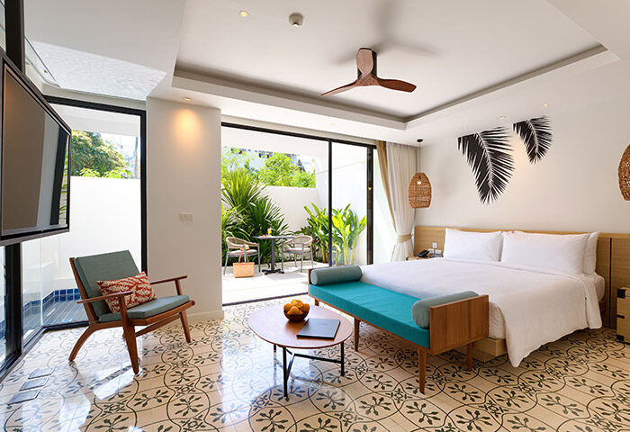 Outrigger Surin Beach Resort, Phuket. Top gay hotel room with bed, chair, and patio. Thailand travel for gay men, perfect for TikTok.