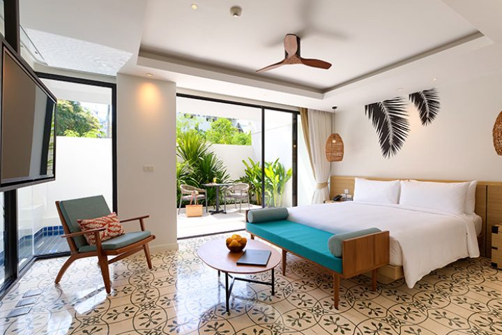 Outrigger Surin Beach Resort, Phuket. Top gay hotel room with bed, chair, and patio. Thailand travel for gay men, perfect for TikTok.