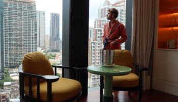 Gay traveler in robe at The Standard, Bangkok Mahanakhon. City center hotel room view. Top gay hotels in Bangkok, Thailand.