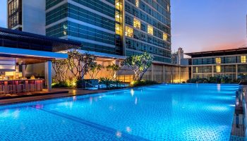 Pullman Bangkok King Power hotel's biggest swimming pool at dusk. Top gay hotel in Bangkok for gay men travelers.