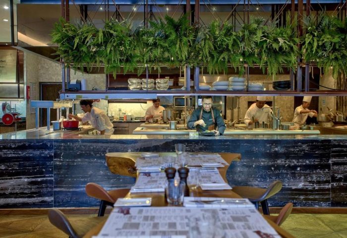 Hilton Sukhumvit Bangkok high-end restaurant. Chefs prepare food in an open kitchen. Top gay hotels in Bangkok offer fine dining.