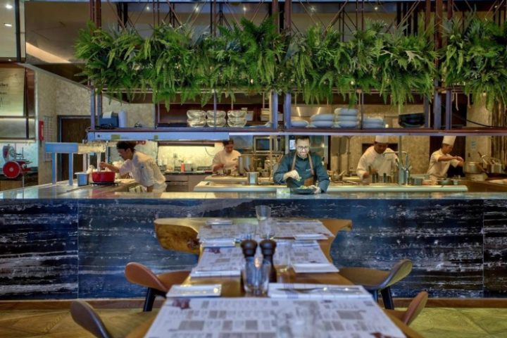 Hilton Sukhumvit Bangkok high-end restaurant. Chefs prepare food in an open kitchen. Top gay hotels in Bangkok offer fine dining.