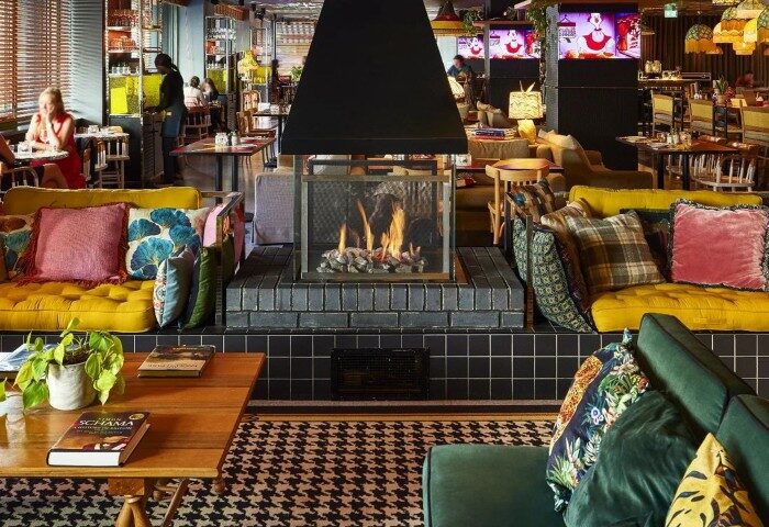 Mama Shelter London's interior. A top gay hotel in Shoreditch with a fireplace, colorful sofas, and a vibrant, welcoming atmosphere.