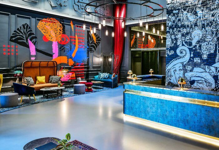 Andaz London Liverpool Street hotel lobby. Stylish design, colorful murals, and modern furniture. A top gay hotel in Shoreditch, London.