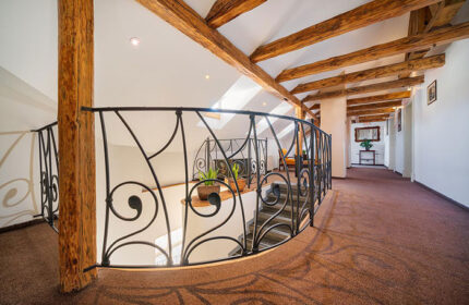 Hotel Leonardo Prague's interior near Charles Bridge. Staircase with iron railing, wooden beams. Top gay hotels in Prague.