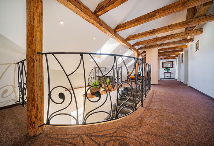 Hotel Leonardo Prague's interior near Charles Bridge. Staircase with iron railing, wooden beams. Top gay hotels in Prague.
