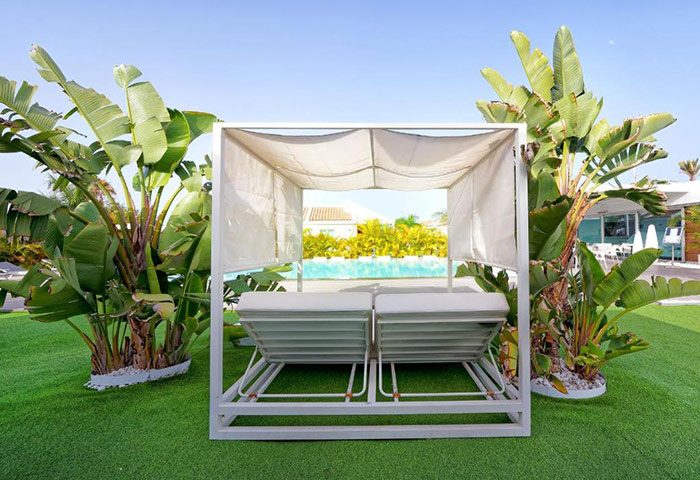 Adults-only gay men's hotel. Daybeds by the pool at Seven Hotel & Wellness in Gran Canaria. Tropical plants surround the relaxation area.