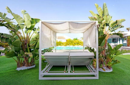 Adults-only gay men's hotel. Daybeds by the pool at Seven Hotel & Wellness in Gran Canaria. Tropical plants surround the relaxation area.