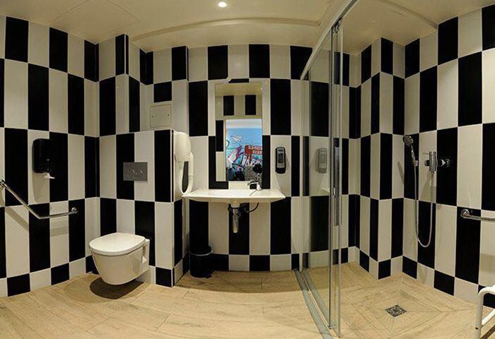 The 3 Ducks Eiffel Tower by Hiphophostels bathroom. Black and white tiled walls, toilet, sink, and shower. Top gay hostel in Paris city center.