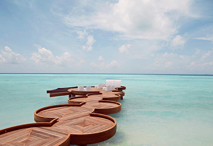 Romantic beach bar at LUX* South Ari Atoll, Maldives. Top gay travel destination. Wooden deck over turquoise water. Gay-friendly resort.