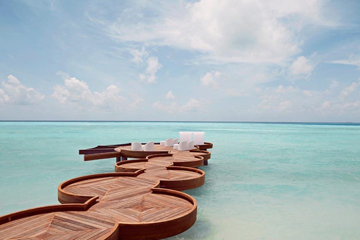 Romantic beach bar at LUX* South Ari Atoll, Maldives. Top gay travel destination. Wooden deck over turquoise water. Gay-friendly resort.