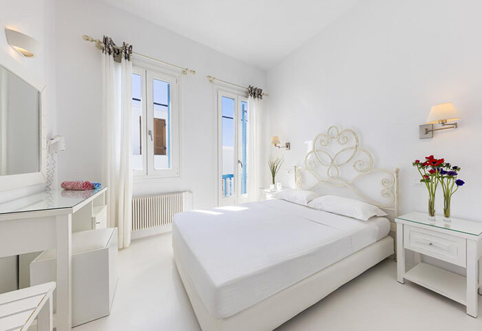 Carbonaki Hotel room, Mykonos. Honeymoon suite with white decor, double bed, and flowers. Ideal for gay couples in Mykonos Town, Chora.