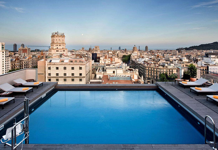 Rooftop pool at NH Collection Barcelona Gran Hotel Calderon. Top Instagramable gay hotel in Barcelona with city views and lounge chairs.