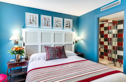 Les Tournelles Hotel room in Paris' Marais gayborhood. Blue walls, striped bedspread, and tiled shower. Instagram-able gay hotel.