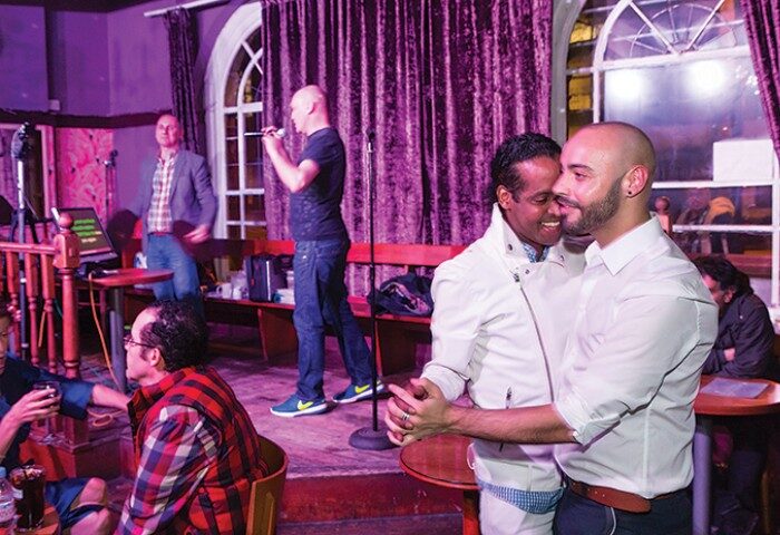 Central Station gay bar, Kings Cross, London. Gay couple embracing, karaoke in progress. Top gay bar for pre-drinks, gay travel advice.