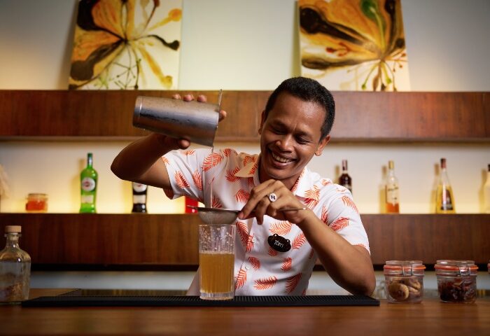 Garrya Tongsai Bay Samui's top gay cocktail bar: Bartender smiles while pouring a cocktail. Koh Samui gay travel.