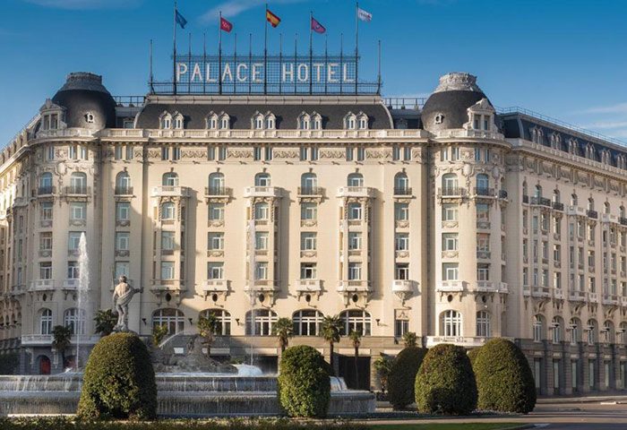 The Westin Palace, Madrid: Top luxury gay honeymoon hotel in Madrid city center. Facade view with flags, fountain, and manicured bushes.