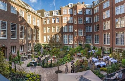 Sofitel Legend The Grand Amsterdam courtyard. Top luxury gay hotel on canal. Outdoor dining, lush gardens, and historic architecture.