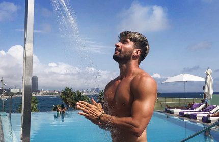 Gay travel: Man at W Barcelona beachfront hotel pool. Top luxury gay hotel in Barcelona. Enjoying the outdoor shower, beautiful view.