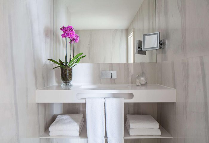 Cool bathroom design in Lisbon's Tivoli Avenida Liberdade. Top luxury gay hotel with orchid, towels, and mirror. Gay travel advice.