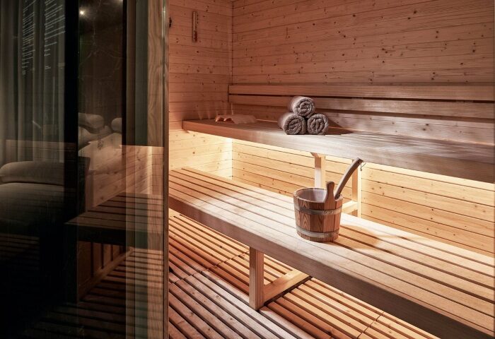 Academias Hotel's sauna. Luxury gay hotels in Athens offer wellness. Wooden sauna interior with bucket, towels, and benches. Relaxing spa.