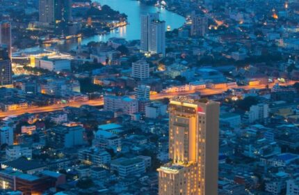 Bangkok Marriott Surawongse, a top luxury gay hotel in Silom, city center. Aerial view of the hotel at night with Bangkok's skyline.