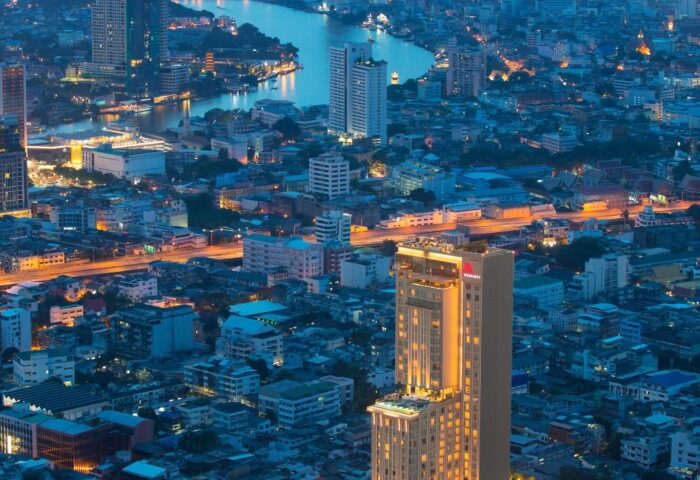 Bangkok Marriott Surawongse, a top luxury gay hotel in Silom, city center. Aerial view of the hotel at night with Bangkok's skyline.