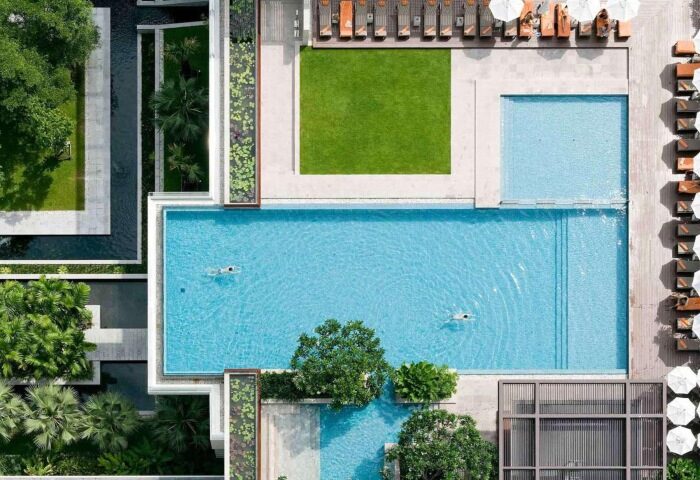 Aerial view of Pullman Bangkok King Power, a top luxury gay hotel near gay saunas. Pools, greenery, and lounge areas create a relaxing atmosphere.