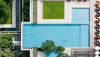 Aerial view of Pullman Bangkok King Power, a top luxury gay hotel near gay saunas. Pools, greenery, and lounge areas create a relaxing atmosphere.
