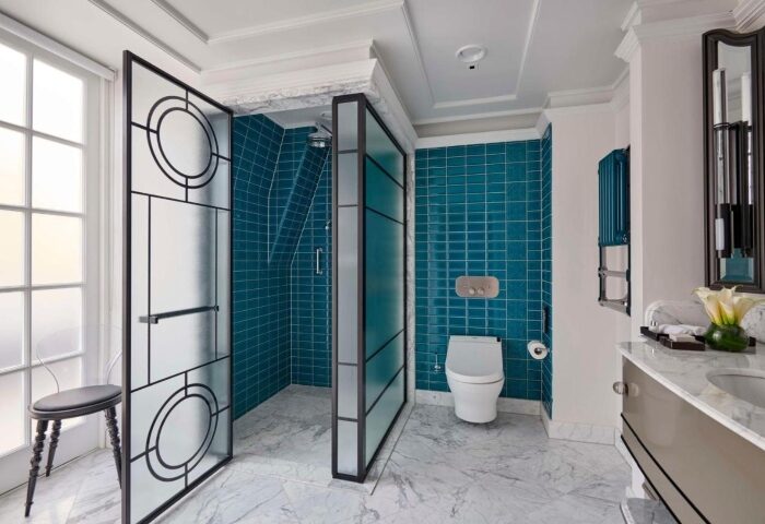 Great Scotland Yard Hotel's luxury honeymoon suite bathroom. Teal tiles, marble floors, & glass shower screen. Top gay London hotels.