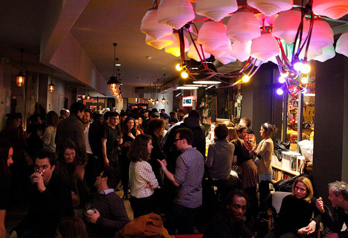 Les Piaules, top party hostel in Paris near gay bars/saunas. People socializing in the hostel's common area. Great spot for gay travelers.