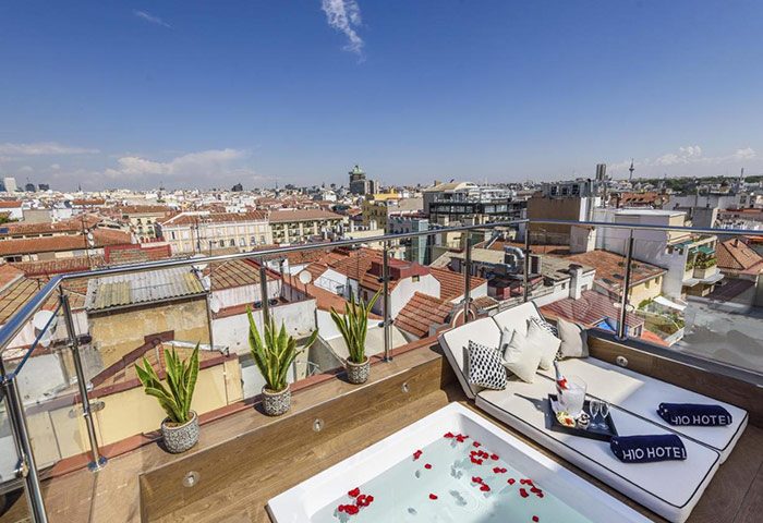 Rooftop terrace at H10 Villa de la Reina Boutique Hotel, a top gay honeymoon hotel in Madrid's Chueca. Hot tub, daybed, city view.