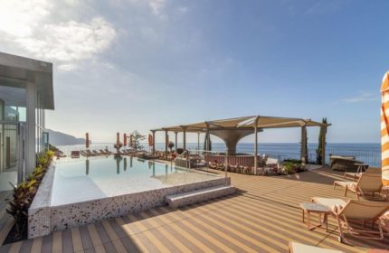 NEXT Hotel Madeira rooftop pool view. Gay beach hotel in Portugal with ocean views, lounge chairs, and bar area. Top gay hotel.