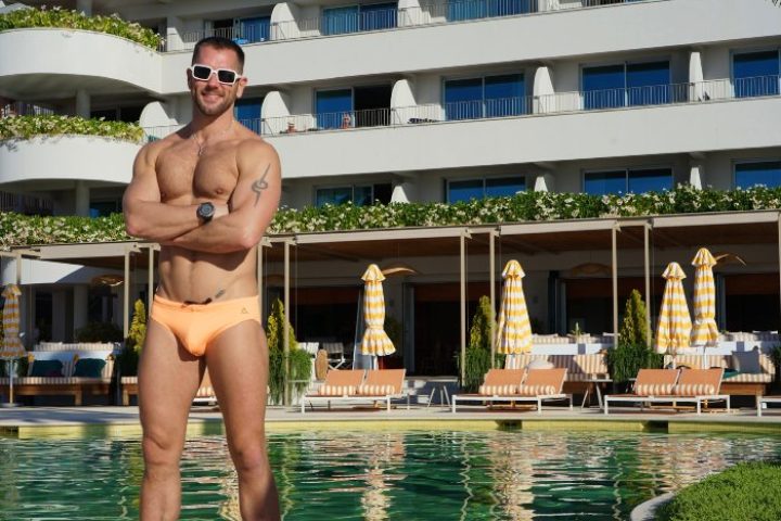 Gay travel: Muscular man at NEXT Hotel Madeira, Portugal. Popular gay hotel with pool and umbrellas. Top rated gay destination.