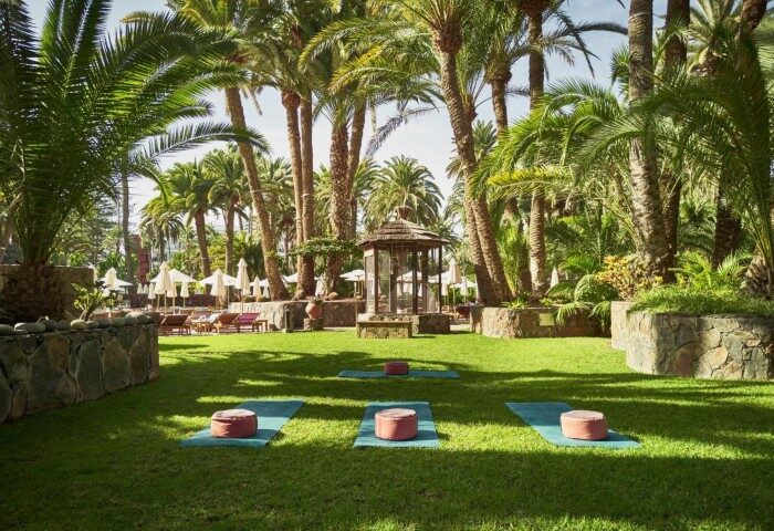 Seaside Palm Beach hotel yoga area. Gay-friendly wellness beachfront hotel in Gran Canaria with palm trees, mats, and meditation gazebo.