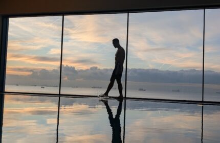Gay luxury hotel JW Marriott Istanbul Marmara Sea: man at pool's edge, silhouetted against a sunset view of the Marmara Sea. Wellness.