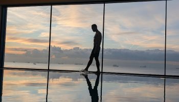 Gay luxury hotel JW Marriott Istanbul Marmara Sea: man at pool's edge, silhouetted against a sunset view of the Marmara Sea. Wellness.
