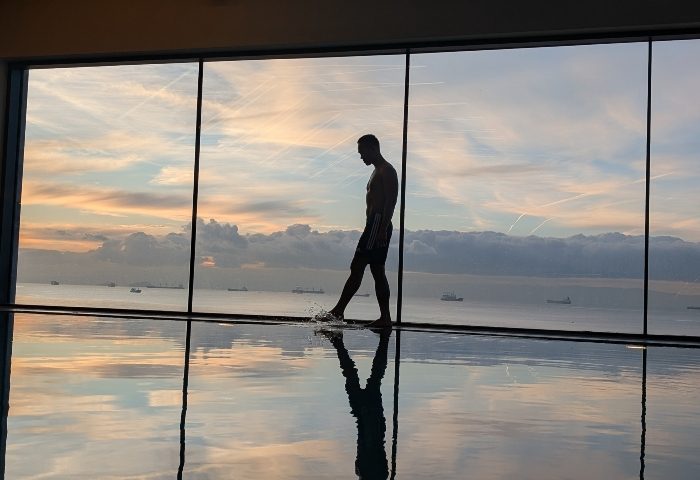 Gay luxury hotel JW Marriott Istanbul Marmara Sea: man at pool's edge, silhouetted against a sunset view of the Marmara Sea. Wellness.