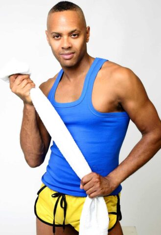 Touch2Massage by Arnie: Gay massage spa model in blue tank top and yellow shorts holding a towel. Gay travel advice.