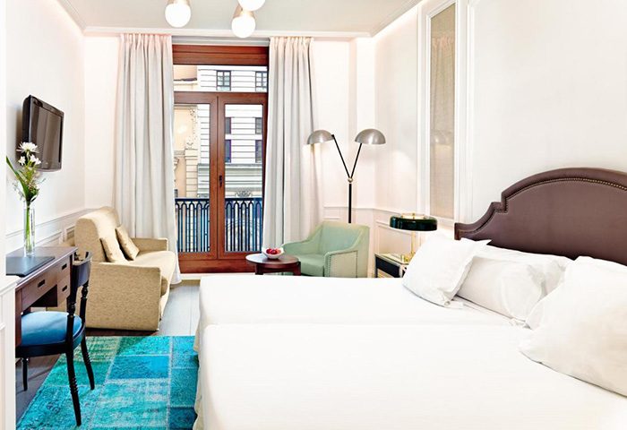 Triple room at H10 Villa de la Reina Boutique Hotel in Madrid's Chueca gayborhood. Modern decor with balcony, perfect for 3 adults' gay travel.