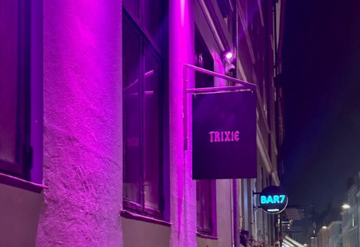 Trixie Copenhagen's vibrant nightlife. Gay travel advice: Trixie bar sign with purple lighting and Bar7 sign. Copenhagen gay bar scene.