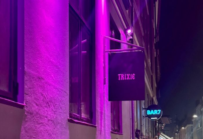 Trixie Copenhagen's vibrant nightlife. Gay travel advice: Trixie bar sign with purple lighting and Bar7 sign. Copenhagen gay bar scene.