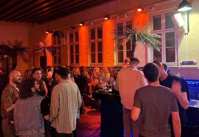 Trixie Copenhagen: Gay men at a bar in Copenhagen, Denmark. People are chatting and drinking in a warmly lit, stylish interior.
