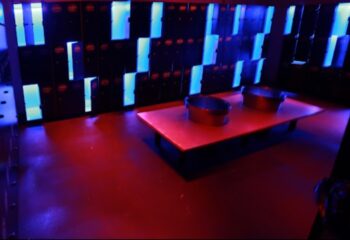 Trombeta Bath Lisbon locker room. Gay travel advice. Lockers with blue lights, table with two metal tubs. Red floor. Gay sauna in Lisbon.