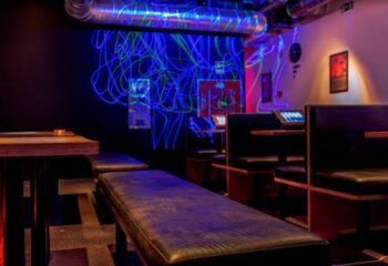 Trombeta Bath, Lisbon: Interior view of the gay bathhouse with benches, tables, and neon lighting. A popular gay travel destination.